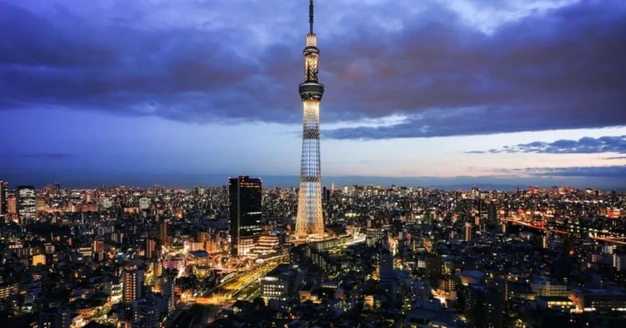 Der beleuchtete Tokyo Skytree in der Abenddämmerung über der flachen Stadt unter violettem Abendhimmel