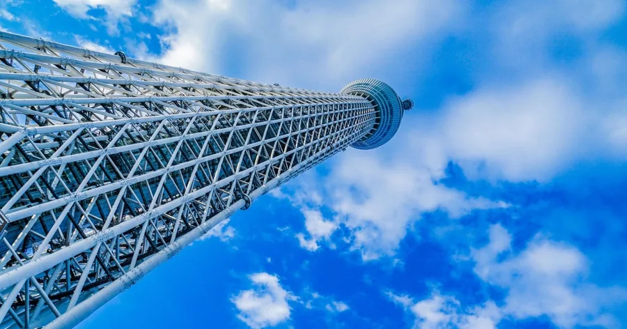 Blick senkrecht nach oben am weißen Stahlgitter des Tokyo Skytree in einen blauen Himmel mit Wolken