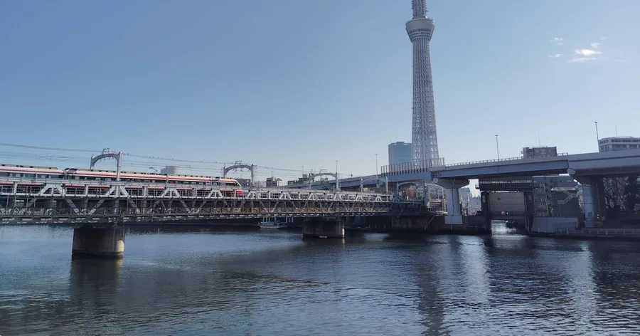 Der Tokyo Skytree hinter einer Eisenbahnbrücke über den Sumida-Fluss an einem klaren Tag